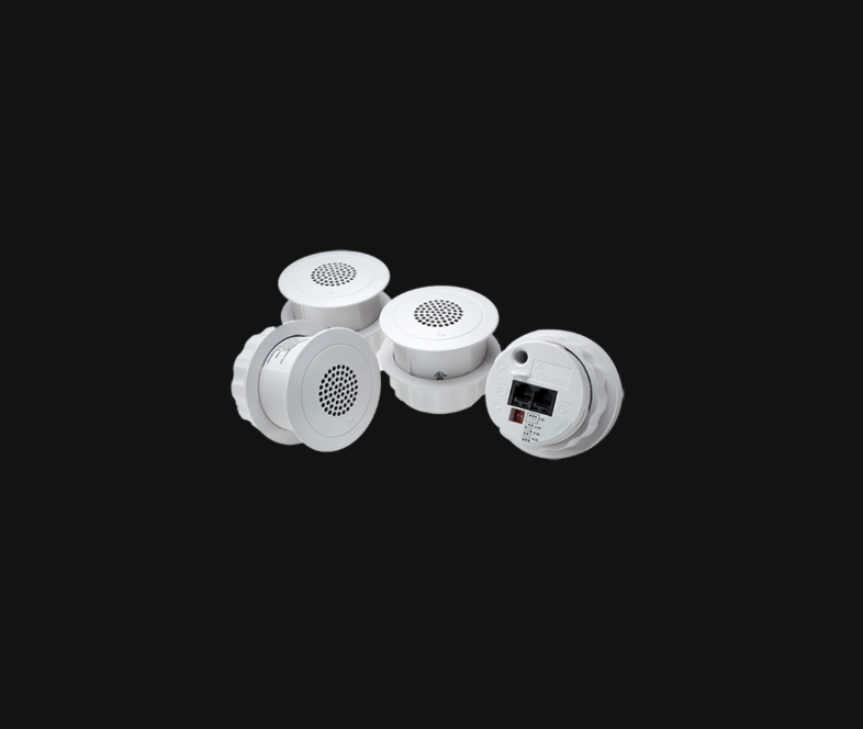 Four round white ceiling sound masking emitters, one turned to show its network jack and level switches.